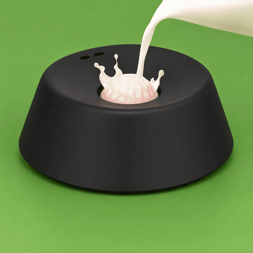 Clero black pet bowl with central raised design and milk being poured on green background